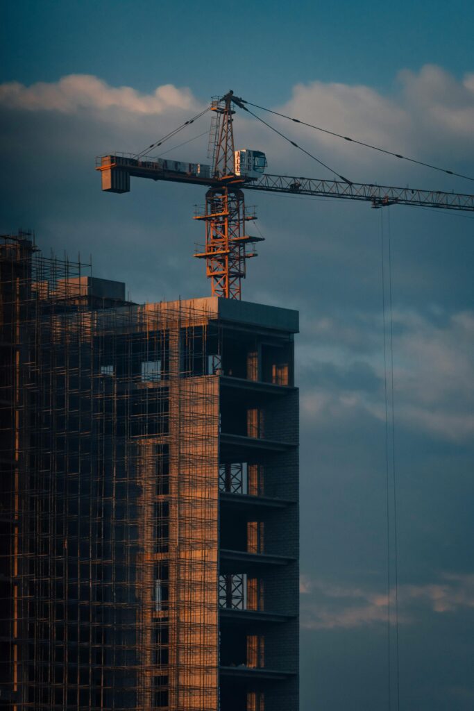 Silhouetted construction site with crane against dawn sky, symbolizing urban development.