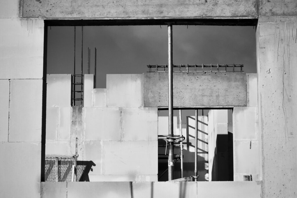 Monochrome image showcasing a construction site in progress, featuring scaffolding and concrete walls.