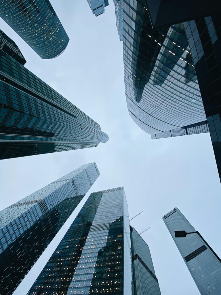 From below of modern skyscrapers with glass mirrored windows located in business district against blue cloudy sky