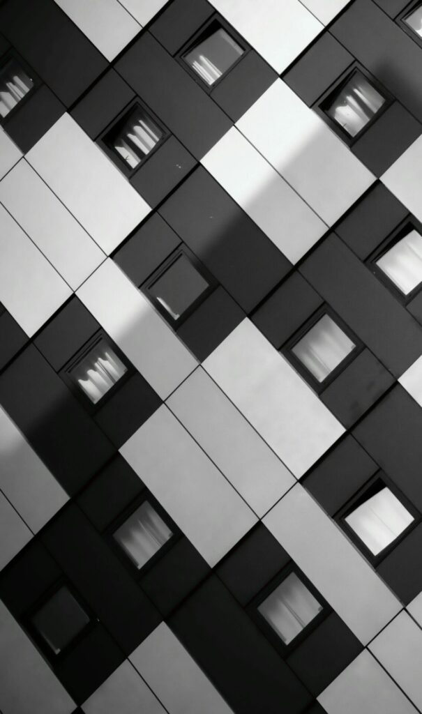 A striking monochrome image of a modern building's geometric facade with windows.