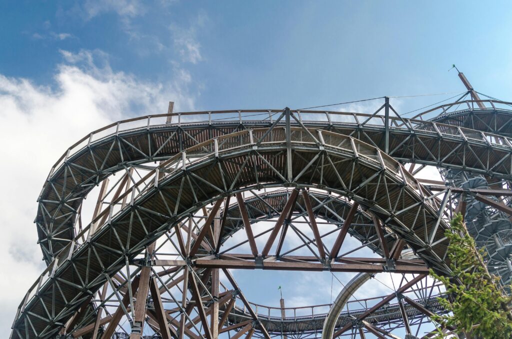 A beautifully constructed metal walkway with wooden elements spirals against a bright blue sky.