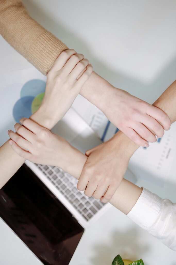 Close-up of diverse hands united over a laptop symbolizing teamwork in an office environment.